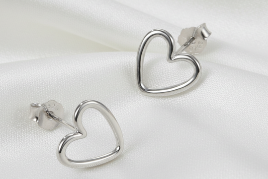 Silver heart-shaped earrings on a light beige background