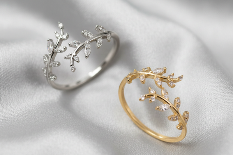 Two leaf-shaped rings, one gold and one silver, on a white background