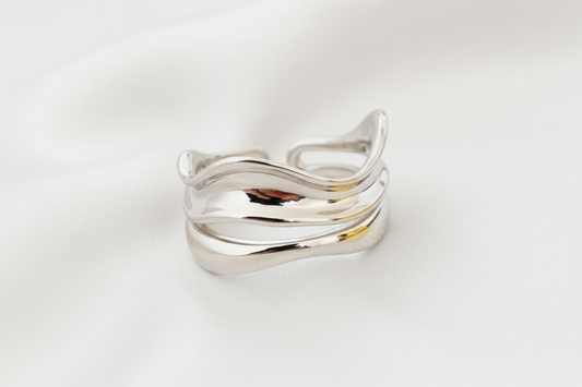 Silver ring with wavy design on a white surface