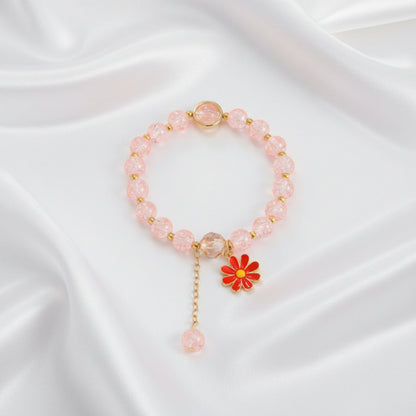 Pink beaded bracelet with a red flower charm on a white background