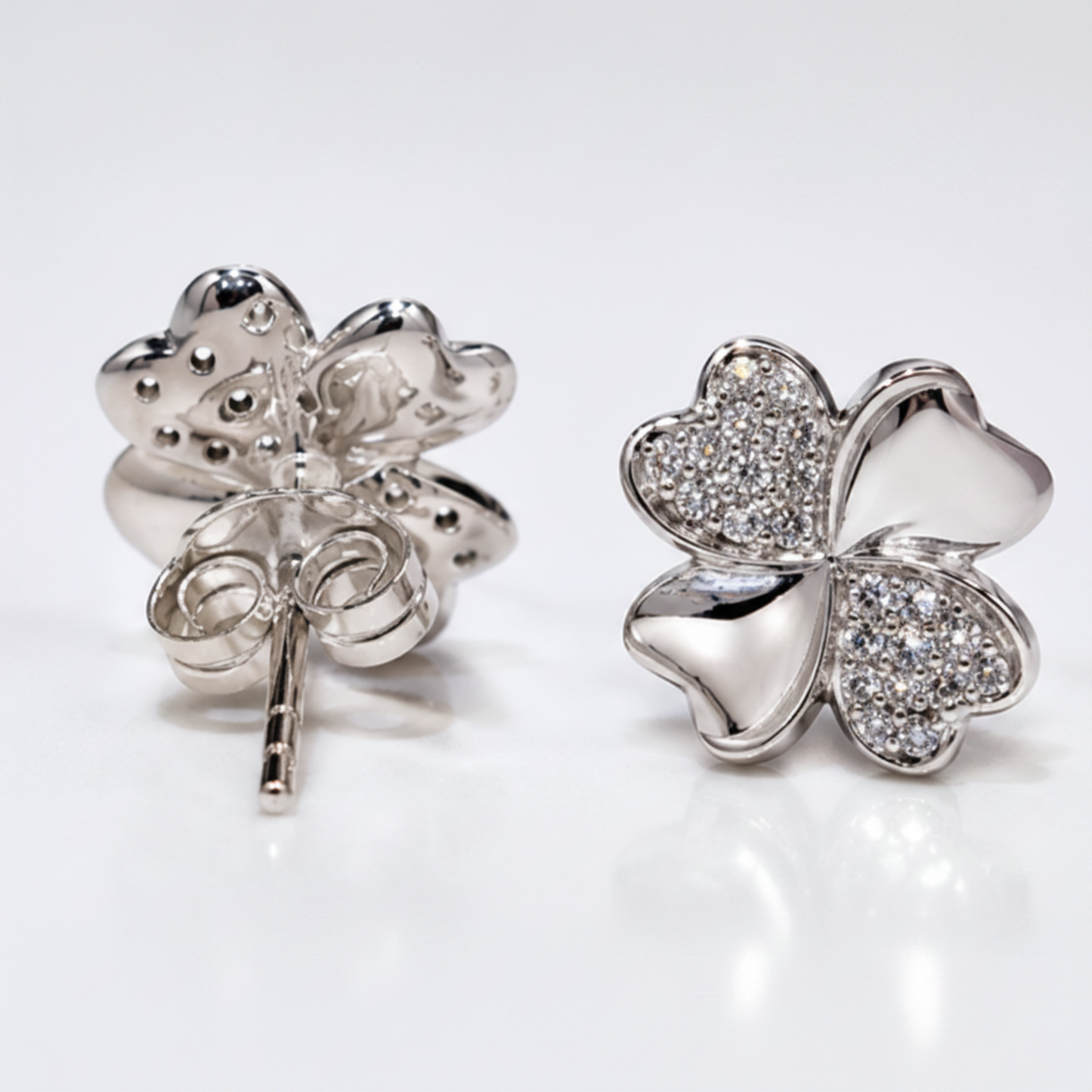 Four leaf sterling silver stud earrings with alternating petals polishes and cubic zirconia on white background
