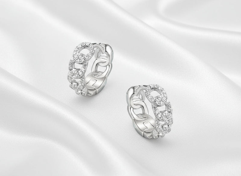 Pair of silver earrings with intricate designs on a light blue background