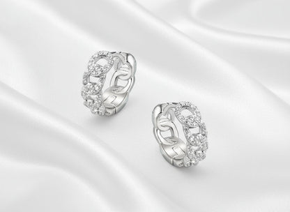 Pair of silver earrings with intricate designs on a light blue background