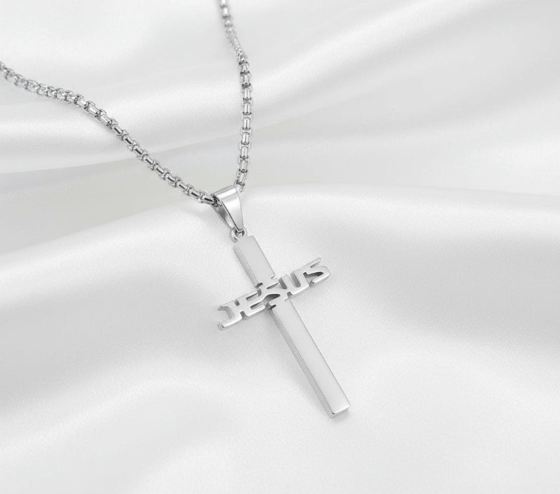 Silver cross pendant with 'JESUS' engraving on a gray background