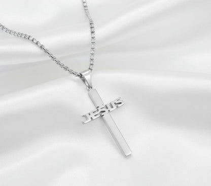 Silver cross pendant with 'JESUS' engraving on a gray background