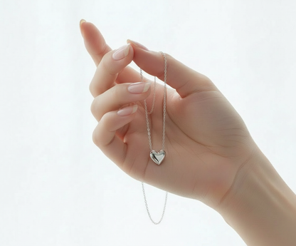 Feminine hand holding delicate heart necklace