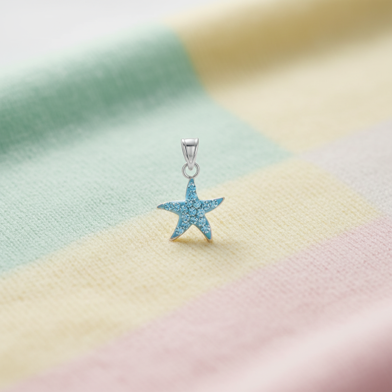 Blue crystal starfish pendant in silver on a child's blanket.