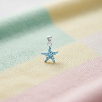 Blue crystal starfish pendant in silver on a child's blanket.