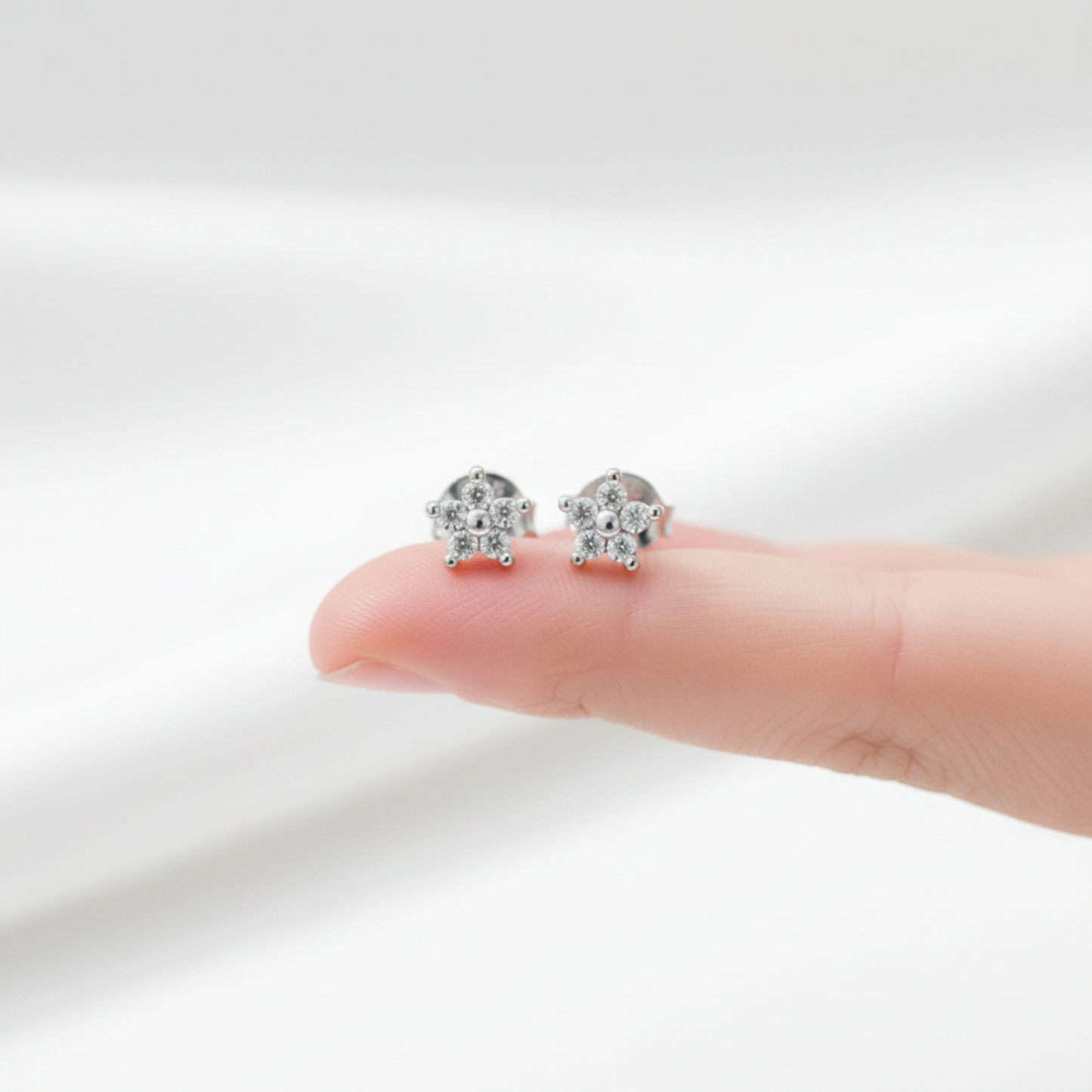 Flower ear studs on fingertip