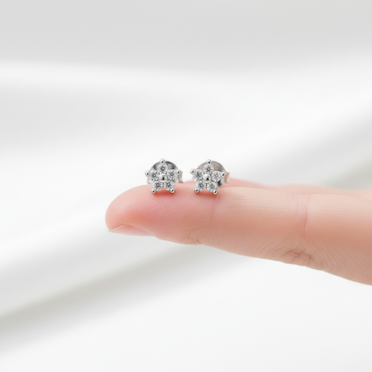 Flower ear studs on fingertip