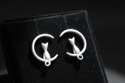Hand holding cat moon earrings