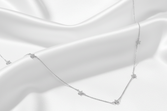 Silver necklace with star-shaped pendants on a white background