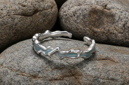 Silver ring with blue accents on a dark rock with a grey background