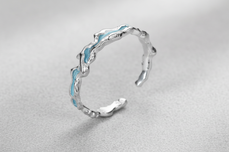 Silver ring with wavy design on a white background