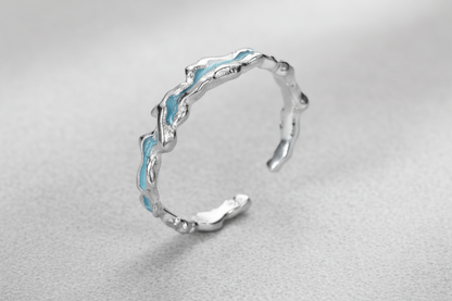 Silver ring with wavy design on a white background