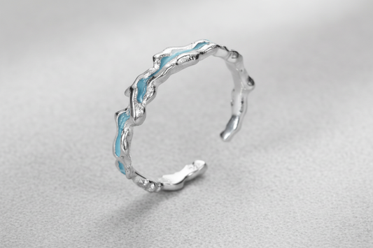 Silver ring with wavy design on a white background