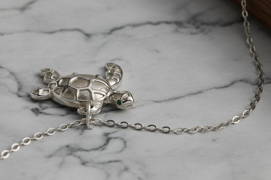 Silver turtle pendant necklace on a white background