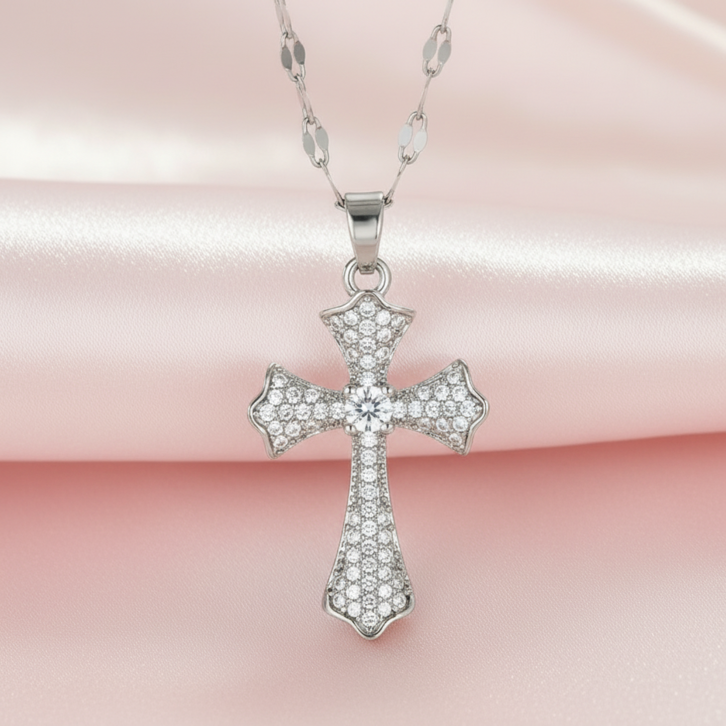 Two cross pendants, one silver and one gold, on a pink background.