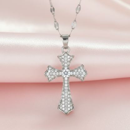 Two cross pendants, one silver and one gold, on a pink background.