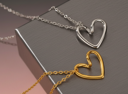 Two heart-shaped pendants, one gold and one silver, on a dark surface.