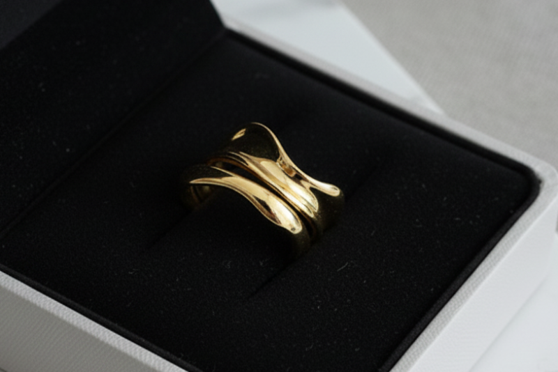 Gold ring in a pink jewelry box on a light gray surface