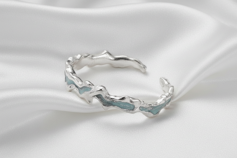 Silver bracelet with wavy design on a white surface