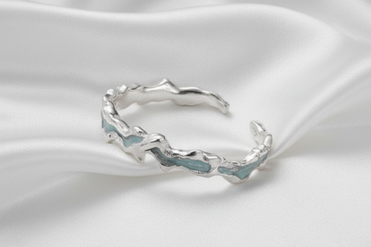 Silver bracelet with wavy design on a white surface