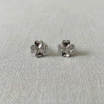 Four-Leaf Clover CZ Stud Earrings on soft grey linen background