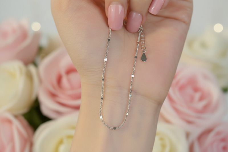 Close-up of a hand holding two delicate silver necklaces.