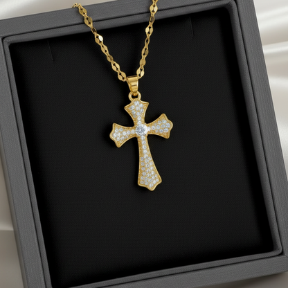 A gold cross pendant necklace paved with small clear stones, displayed on a black jewelry box with a white satin background.