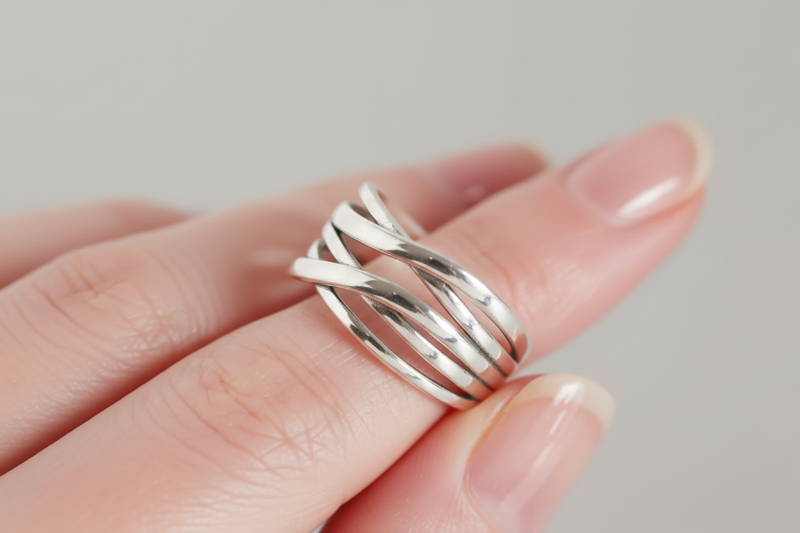Silver ring on a person's finger against a neutral background
