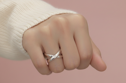 Hand wearing multiple silver rings on a neutral background