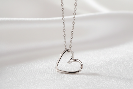 Silver heart-shaped necklace on a white 
surface