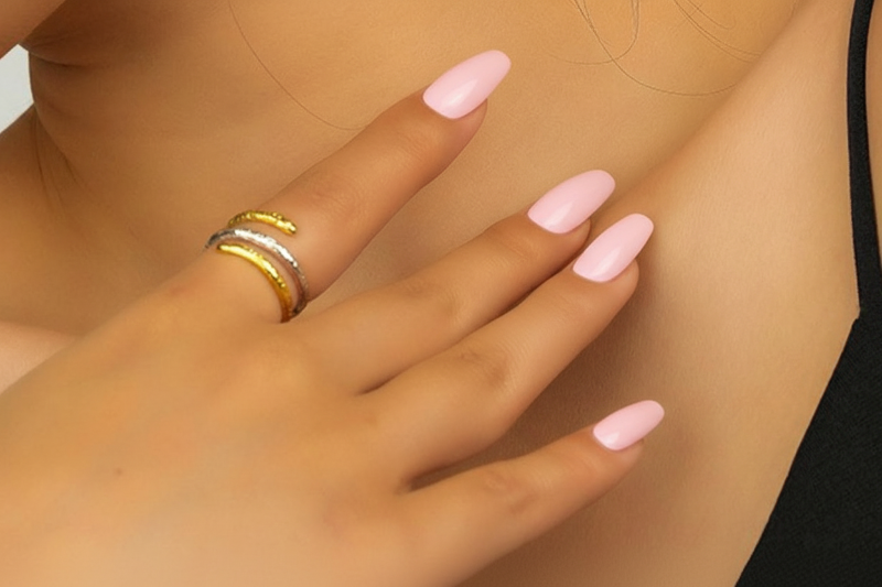 Close-up of a hand with green nail polish and a gold ring, with a tattoo on the wrist.