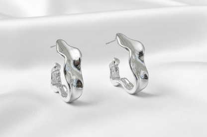 Silver earrings on a white satin background
