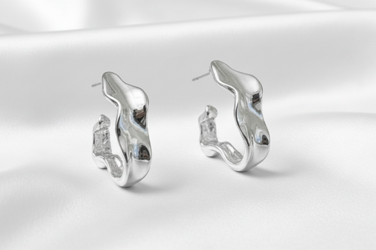 Silver earrings on a white satin background