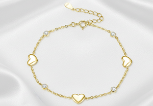 Gold bracelet with heart-shaped charms on a white background