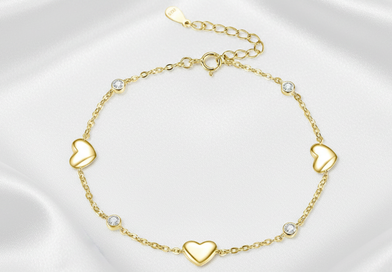 Gold bracelet with heart-shaped charms on a white background