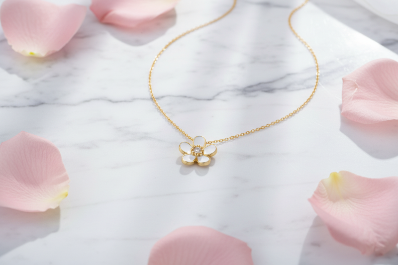 Two flower-shaped necklaces, one gold and one silver, on a white background.