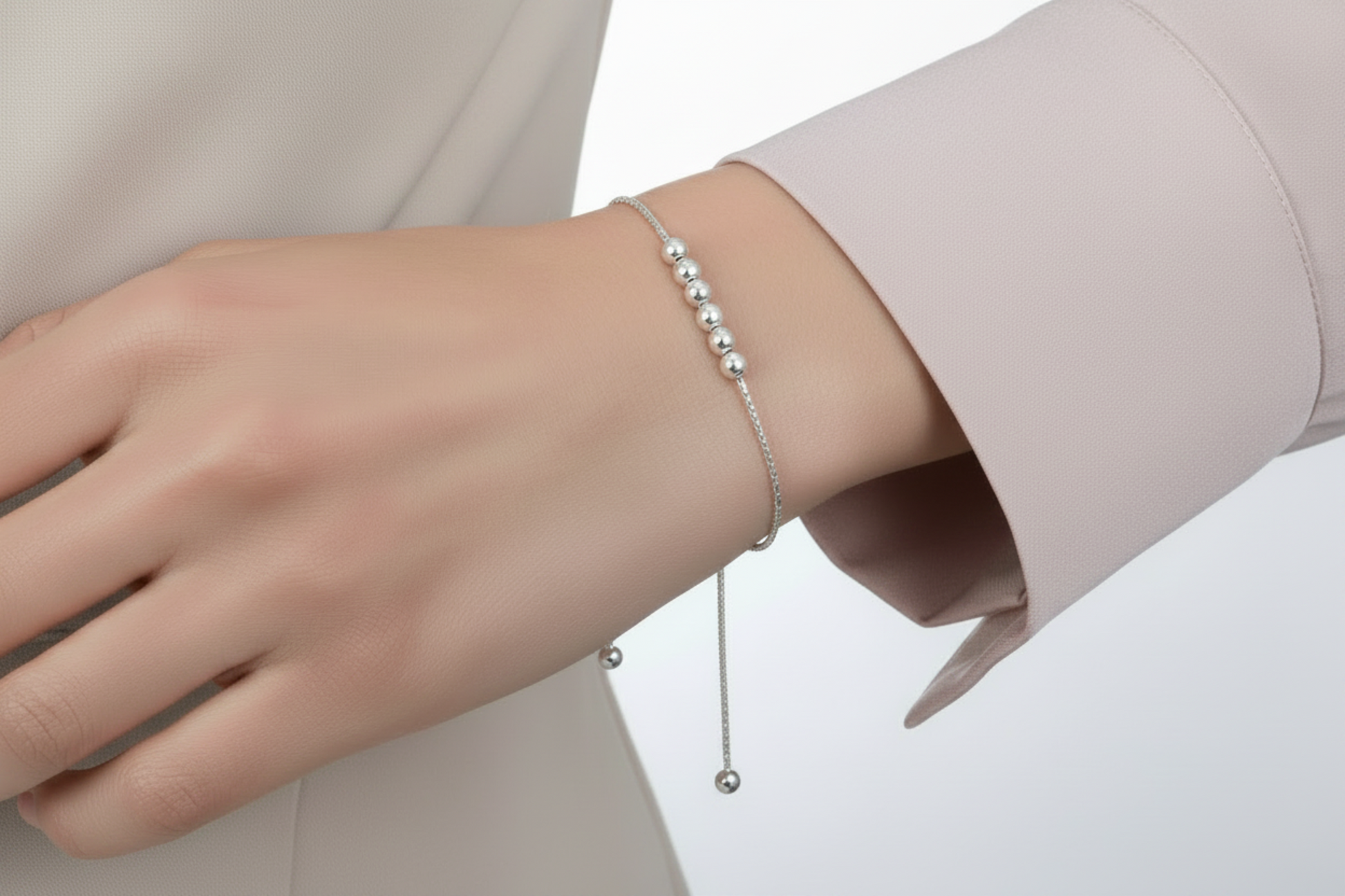 Silver beaded bracelet on a wrist with a white background