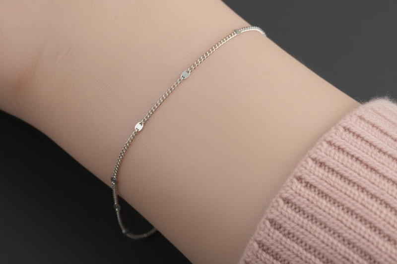 Silver bracelet on a wrist with a neutral background