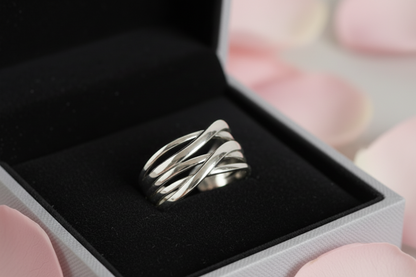 Silver ring in an open jewelry box on a light gray background