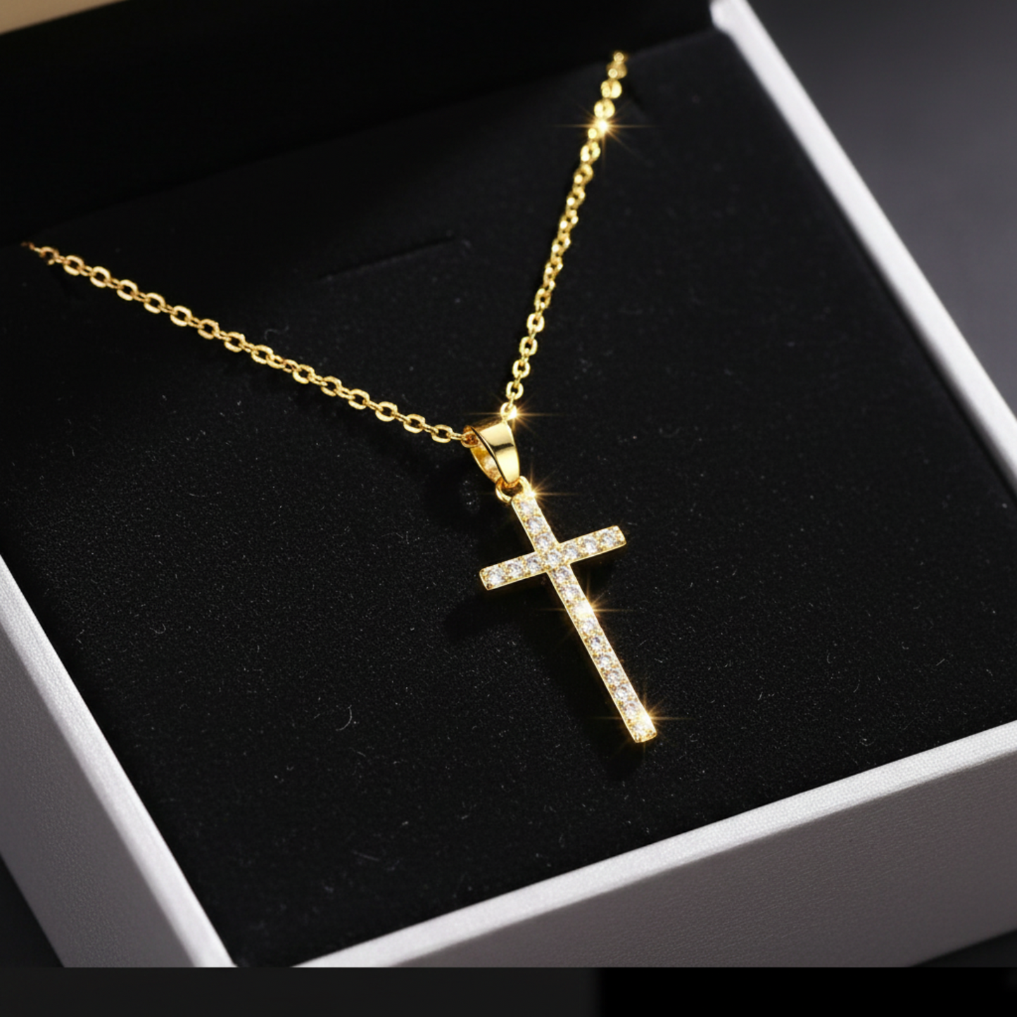Gold cross necklace with cubic zirconia on black insert in a grey jewellery box