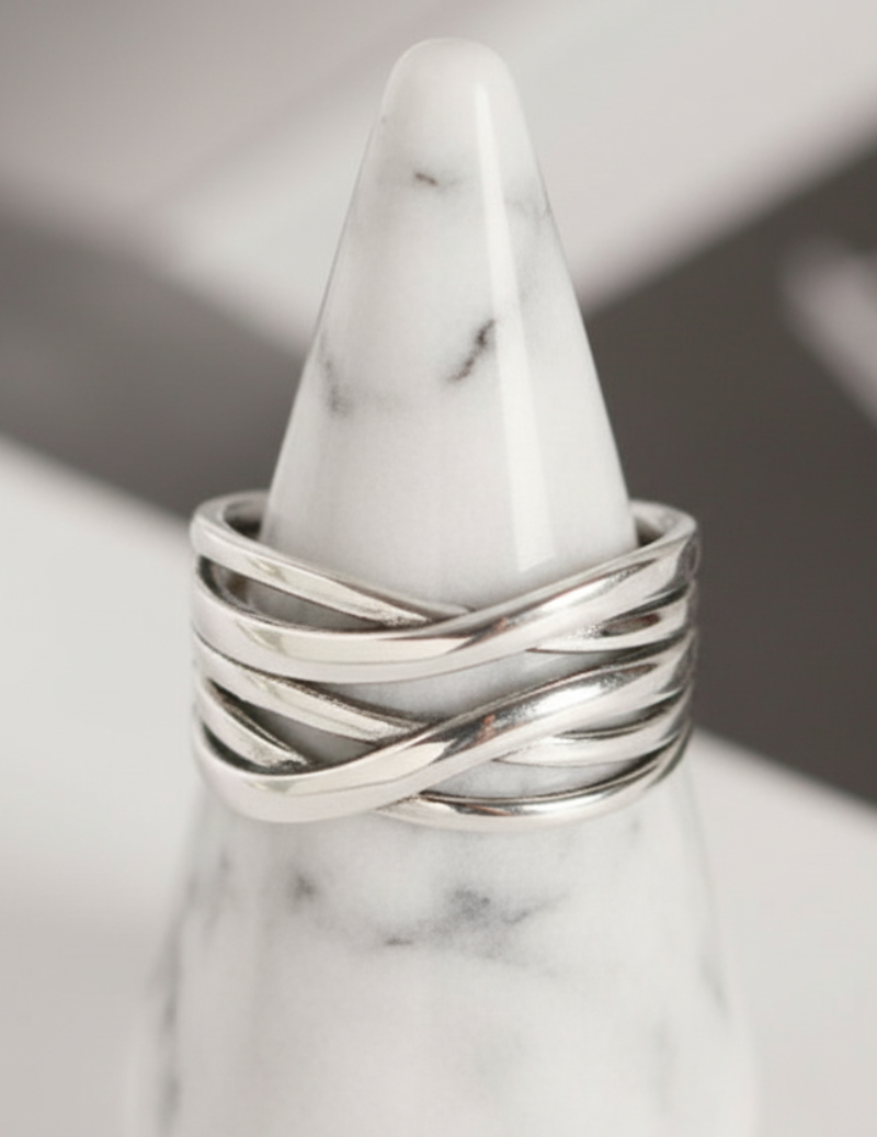 Silver ring on a marble cone against a neutral background