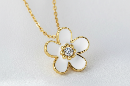 Gold flower-shaped necklace with a diamond on a light gray background