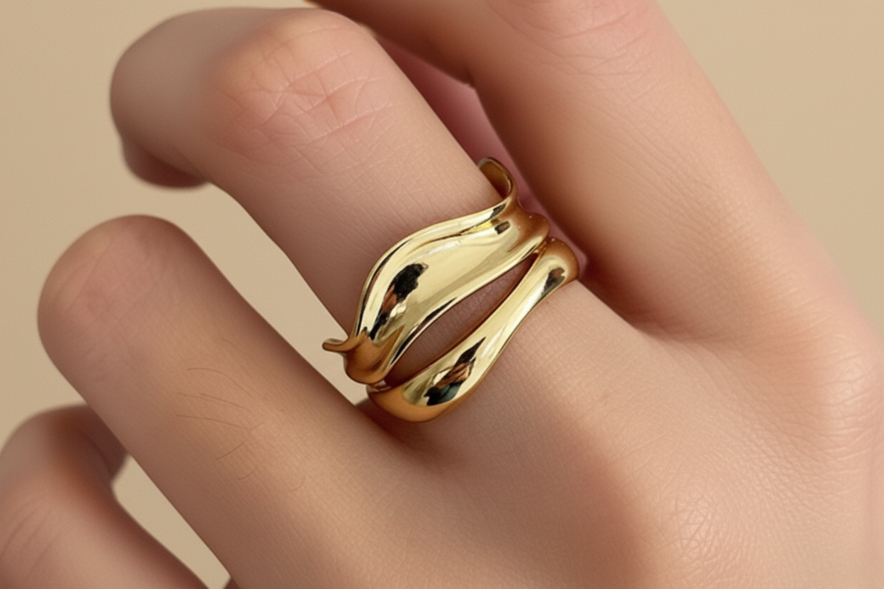 Gold snake-shaped ring on a person's finger with a neutral background