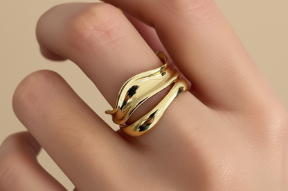 Gold snake-shaped ring on a person's finger with a neutral background