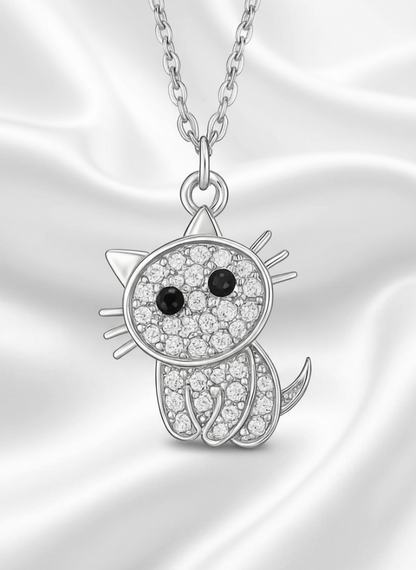 Silver cat-shaped pendant with black and clear gemstones on a white background