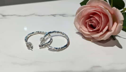 Silver hoops on marble with rose